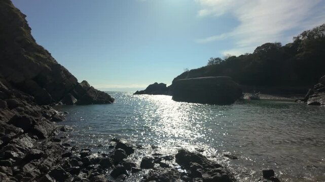A receding tide showing a rocky beach with a boat moored in the harbour of Stackpole Quay on the Pembrokeshire Coast, Wales.