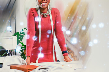 Creative fashion designer smiling while working on sewing project in a bright studio adorned with digital icons