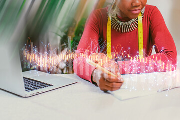 Creative designer sketches new fashion ideas while using a laptop in a bright and inspiring workspace during the day