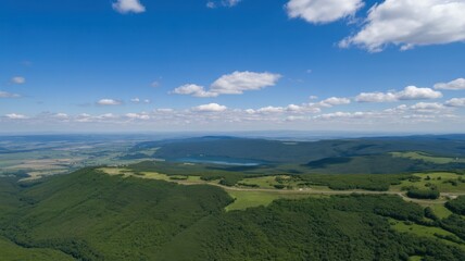 Obraz premium Breathtaking aerial view of the green mountain range and valley under a cloudy blue sky