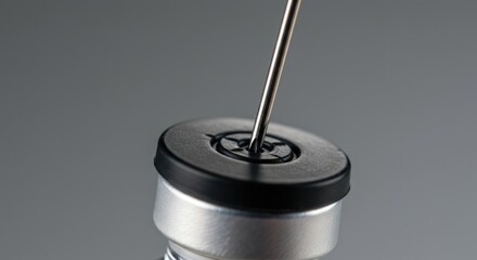 Sharp needle pierces sterile rubber stopper on medical vial ready for injection or sample collection