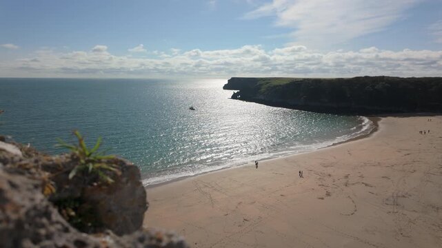 Establishing shot of Barafundle Bay Beach on the Pembrokeshire coast, Wales on a bright summers day with a calm sea.