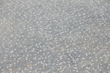Textured cobblestone pavement with various shades of gray, showcasing intricate patterns and natural wear, creating a rustic and timeless outdoor surface for urban environments
