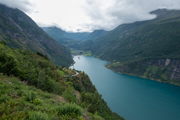 Obraz premium A Ferry boat and small boats on the most beautiful fjord in Norway, Geirangerfjord. Norway