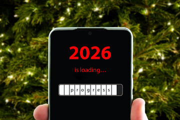 concept of changing the year from 2025 to 2026. smartphone on the computer keyboard with the process of loading the new year. end of 2025