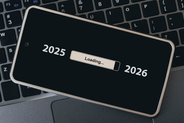 concept of changing the year from 2025 to 2026. smartphone on the computer keyboard with the process of loading the new year. end of 2025