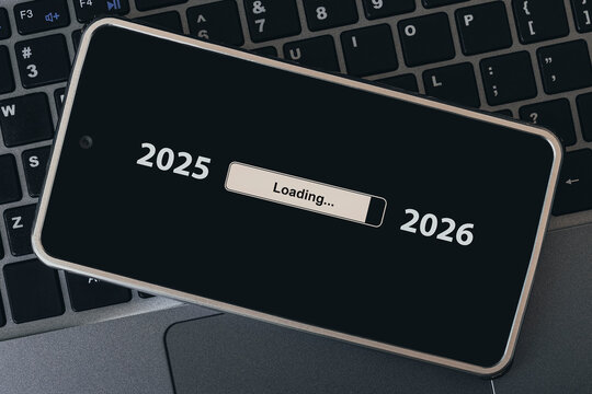 concept of changing the year from 2025 to 2026. smartphone on the computer keyboard with the process of loading the new year. end of 2025
