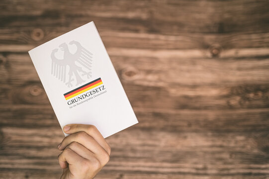 Eine Hand h&auml;lt das Grundgesetz der Bundesrepublik Deutschland &ndash; symbolisiert den Schutz demokratischer Werte und die Bedeutung der Verfassung.