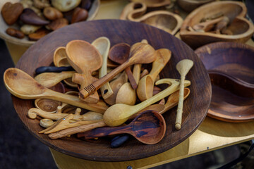 A vibrant display of handcrafted wooden spoons, bowls, and heart-shaped ornaments at a rustic artisan market, highlighting natural wood grain and traditional craftsmanship.