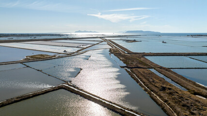 Aerial view of the Trapani salt pans, Sicily, Italy. The salt evaporation ponds are in the foreground, and the Egadi Islands, Favignana and Levanzo, are silhouetted in the background.