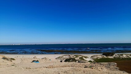 Peaceful Coastal View with Blue Sea and Sandy Cliffs Under Clear Sky
