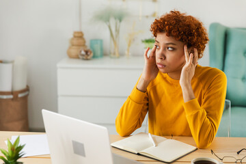 African woman touching temples experiencing stress. Girl at home office tired of working feeling headache sick rubbing temples forehead. Long laptop usage computer vision syndrome. Office syndrome