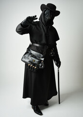 Fototapeta premium Plague Doctor Full length walking Silhouette Portrait of Gothic Halloween Character with Beak Mask, Black Cloak on White Studio Background, Dramatic Dark Costume and Fantasy Horror figure