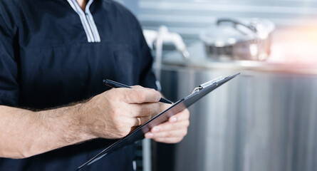 Beer production, Operator uses tablet to check quality and temperature of yeast fermentation in tanker hops and malt