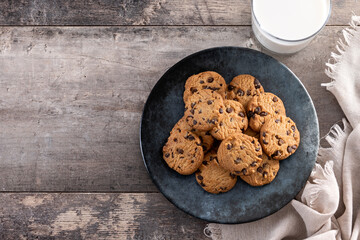 Chocolate chip cookies and milk for breakfast on rustic wooden table. Top view. Copy space