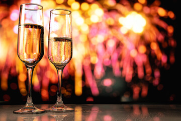 Romantic couple toasting champagne amidst fireworks reflected on terrace during New Year midnight