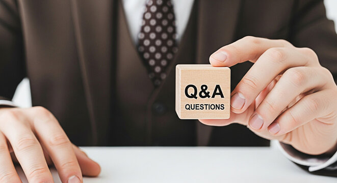Man holding a wooden block with q&a questions printed on it in a business setting suggesting information and answers are readily available