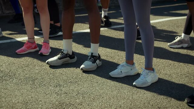 Athletes gather at the starting line, poised for an outdoor run. Their varied athletic footwear is highlighted, emphasizing preparation and readiness for physical activity.
