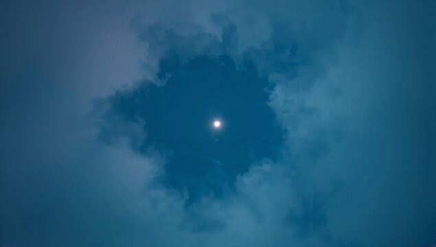 Revealing full moon shining through circular cloud gap in deep blue night sky, with faint star - Powered by Adobe