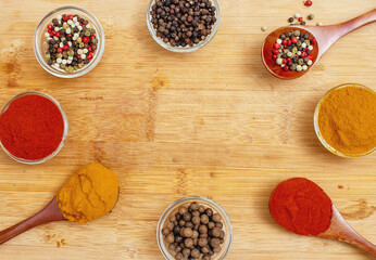 Aromatic spices in wooden spoons and transparent bowls on wooden background. Culinary inspiration.