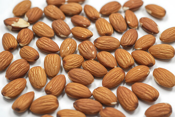 Pile of raw almonds scattered on a white surface isolated