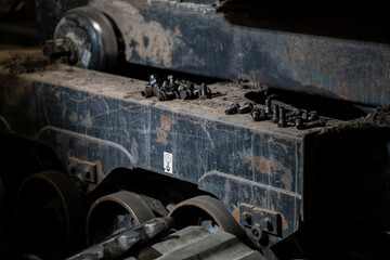 Industrial machine frame with bolts and dirt-covered surface representing construction equipment repair, maintenance, and mechanical engineering environment