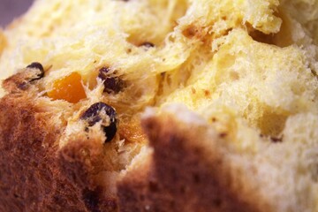 Macro shot of bread texture with raisins and candied orange peel. Detailed close-up of traditional sweet pastry showing soft dough and rich ingredients. Panettone or easter cake.