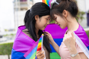 Women teen with colorful LGBTQ pride month rainbow flag, couple female happy smiling enjoy together