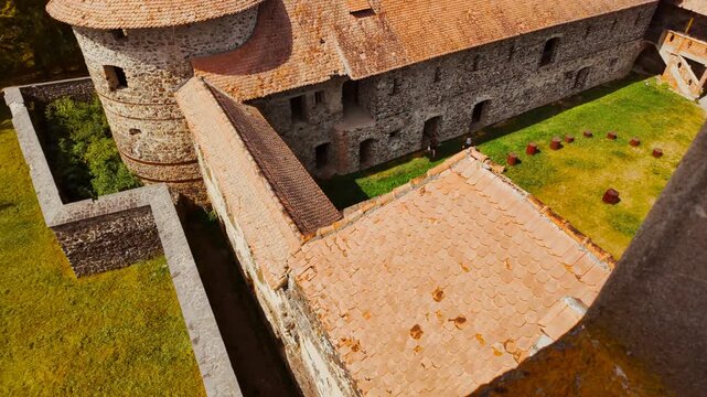 Sukosd-Bethlen Castle, Racos, Brasov, Romania, fortified walls and corner towers in rugged stone overlooking fields and the village