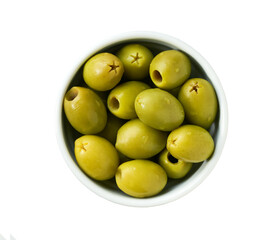 pitted green olives in a white ceramic bowl isolated on a white background, top view.