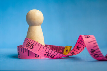 Wooden peg beside pink measuring tape showing healthy lifestyle theme with customizable space for text or ideas.