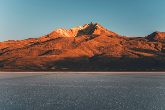 view of the volcano at sunrise by salar de uyuni, bolivia