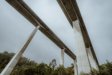 Modern concrete highway viaducts viewed from below in dramatic wide-angle perspective, towering...