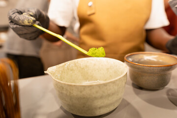 Person adding ceremonial matcha powder to bowl