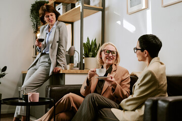 Three middle aged women, including two Caucasian and one with short dark hair, sitting and standing...