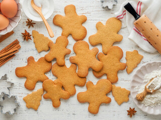 Homemade Christmas gingerbread men cookies with Ingredients for cooking Christmas baking on old white wooden background table. Top view. Christmas holiday kitchen background. Design element.