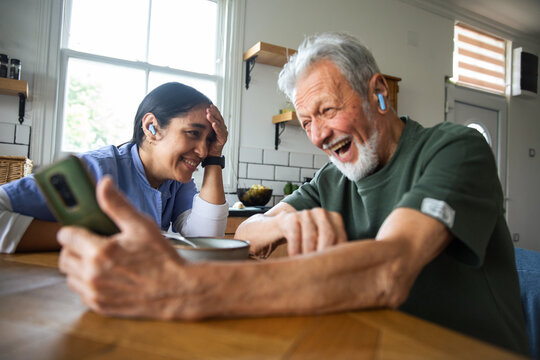 Senior man and caregiver laughing at home