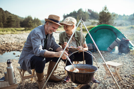 Mature couple cooking outdoors while camping