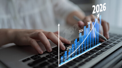 A close-up view of hands typing on a laptop keyboard with a digital graph overlay illustrating...