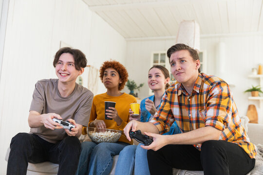 Home party. Cheerful group of friends playing video games at home. Happy diverse group buddies having fun together indoor. Friendship leisure entertainment concept. Young best friends enjoying weekend