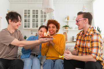 Make a wish. Woman wearing party cap blowing out burning candles on birthday cake. Happy Birthday...