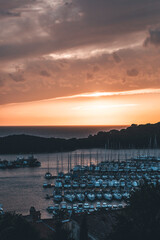 dramatic sunset at the harbour in montona, croatia, with small boats in the water and cloudy sky