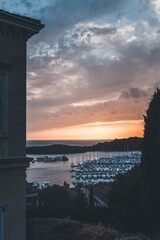 colorful sunset at the beach in montona, croatia, with small boats in the water and cloudy sky