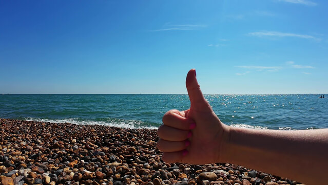 Thumb Up Contentment Hand Gesture at the Seaside - Powered by Adobe