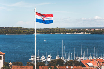 flag of croatia in pula, in front of the sea landscape with boats and rooftops