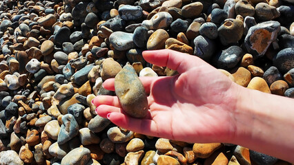 A person reflects by a pile of rocks, holding a significant stone