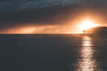 dramatic sunset by the sea in croatia, after a storm with moody clouds, golden sun and the silhouette of the cape