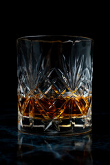 Lowball whisky glass in dark studio environment on dark marble table