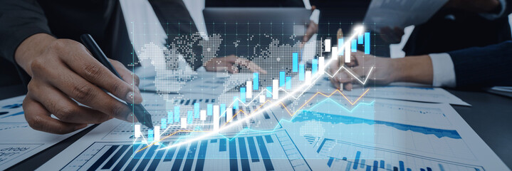 Business professionals engage in detailed analysis of financial data, using graphs and charts in a...