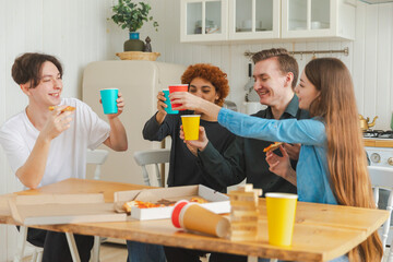 Home party. Friends spending time together having fun laughing communicating at home. Happy diverse group eating pizza drinking beer or lemonade. Mixed race young buddies best friends enjoying weekend
